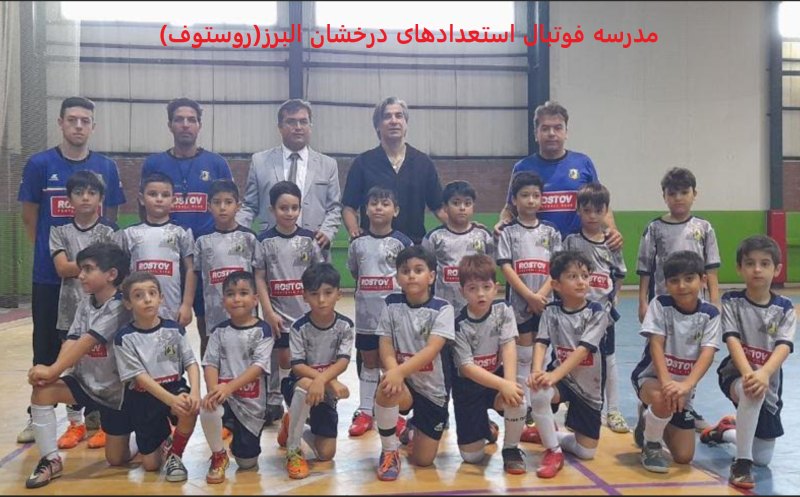 تصویر تیم فوتبال نونهالان مدرسه فوتبال روستوف ایران در سالن با لباسهای طوسی همراه با مربیان و وحید شمسایی